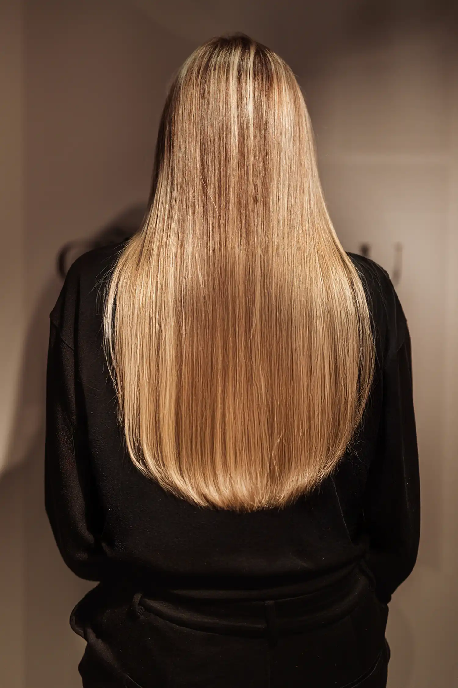 Lang, steil blond haar met een Essential-weaving van Cèlia Blu, van achteren gezien