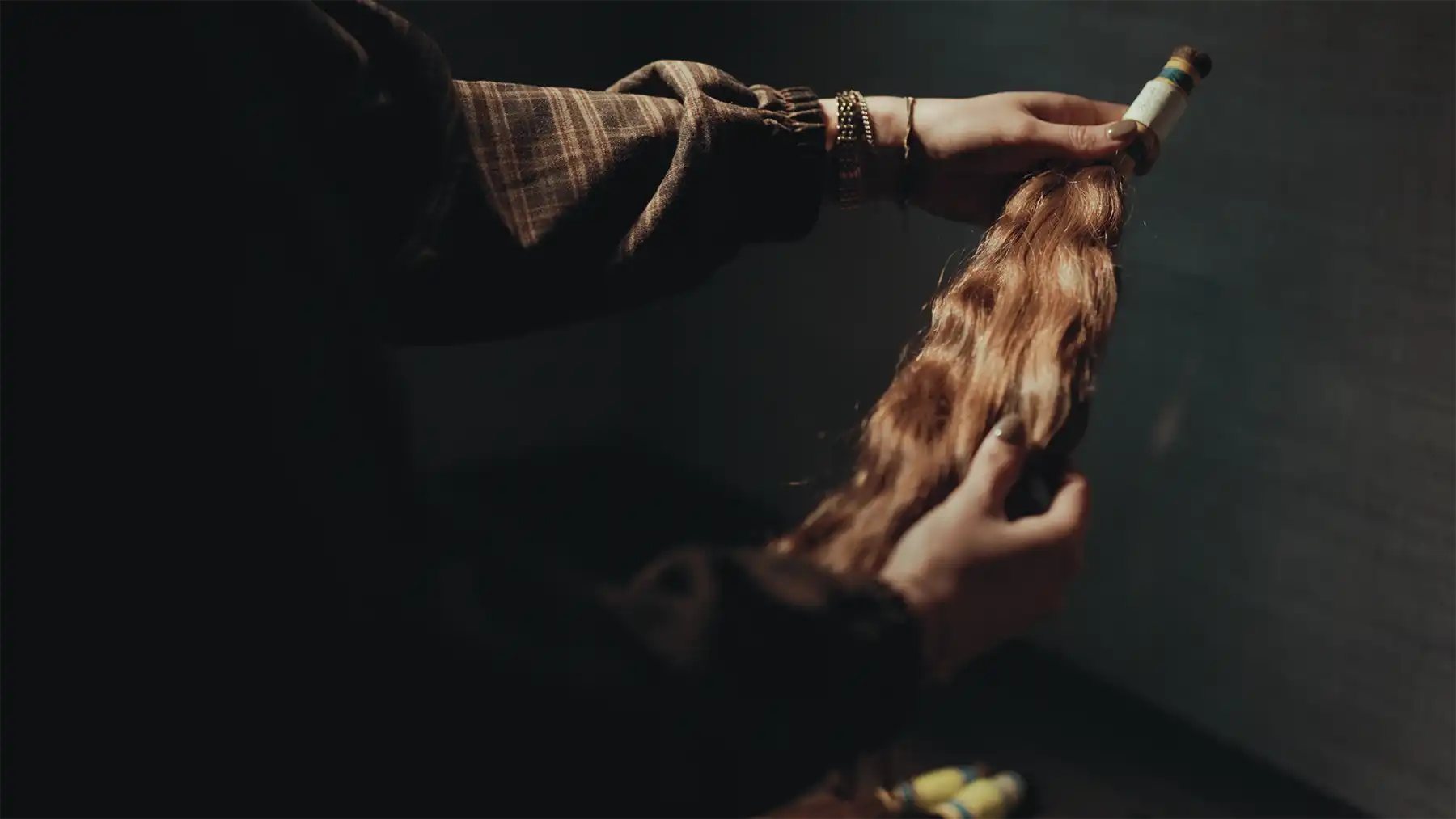 Handen met een staart onbehandeld haar van Cèlia Blu tegen een donkere achtergrond