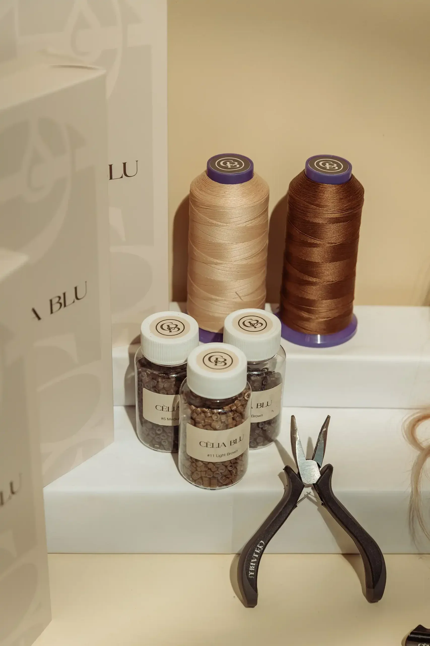Professionele materialen van Cèlia Blu: garenklosjes, potjes met kraaltjes en een tang